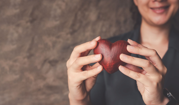 Stock photo of a woman holding a heart-shaped wooden object